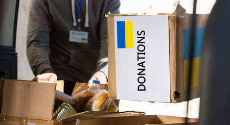 Box with donation clothes and food for ukrainian refugees suffering from war. Charity and Helping poor and needy people.の写真素材