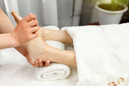 Specialist woman masseur making feet massage procedure to a client woman in spa salon, beauty care and health lifestyle concept.の写真素材