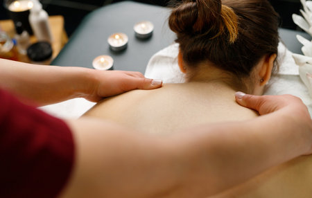 Professional massager doing relax shoulder massage to a young woman lying down on the table for massage in spa salon.の写真素材