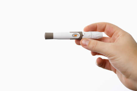 Close up photo of a lancet for checking blood sugar level by glucose meter man holding in his hand on white background.の写真素材