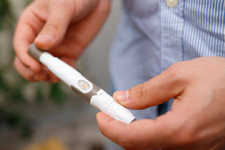 Man holding in his hands lancet for checking blood sugar level by glucose meter, healthcare and diabetes treatment concept.の写真素材