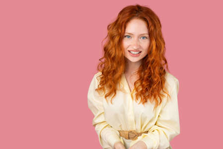 Simpathic redhead young woman with blue eyes posing for the camera with happy facial expression on pink background and copy space.の写真素材