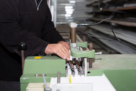 Cropped photo of a worker man standing near the building material making machine and cutting...