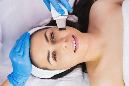 Top view photo of a happy woman face undergoes the rejuvenation face procedure with ultrasonic peeling in clinic beauty salon.の写真素材