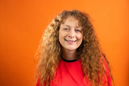 Portrait of joyful redhead pretty young woman fan of fotball in team red t-shirt smiling of beautiful game of her football team.の写真素材
