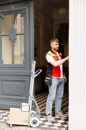 The courier in front of the door calls the intercom to inform the person that the parcels have arrivedの写真素材