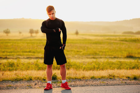 Sportiv man runner resting after training outdoors, looking watch with a beautiful background