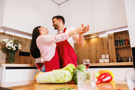 Wide banner panoramic view of overjoyed young Caucasian man and woman have fun dancing in modern kitchen at home.の写真素材