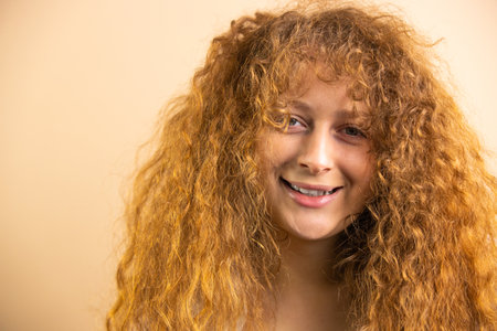 Picture of a funny joyful redhead pretty smiling woman looking at the camera over a golden background, copy space.の写真素材