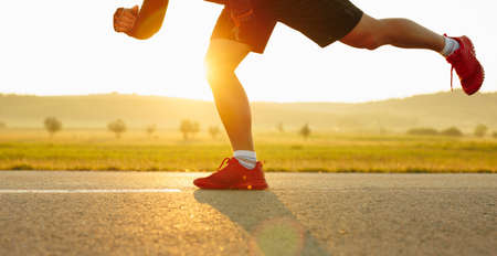 Sprinting man runner sprinter athlete running shoes and legs on track and field lane run race competing fast panoramic banner background.の写真素材