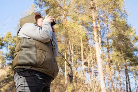 Side view photo of a photographer woman in winter cold sunny day making nature photo and spending good day outdoors.の写真素材