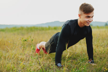 Push up fit man doing arm workout exercising bodyweight exercise pushup outdoor in nature with a big smileの写真素材