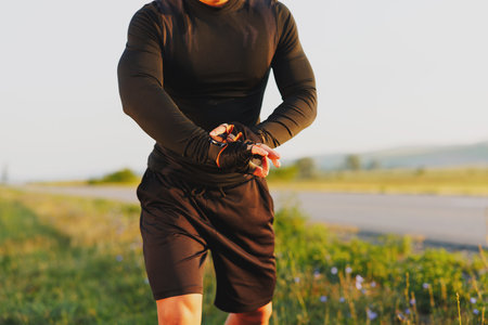 The body of a young athlete running and checking the time on the smart watch on his hand.の写真素材