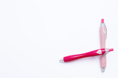 Two pink pens that overlap on a white background. The sign of cancer is drawn on the pen, the campaign against cancer.の写真素材