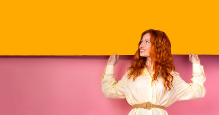 Happy cheerful young woman wearing her red hair looking one side with joyful and charming smile. Ginger student girl relaxing indoors after collegeの写真素材