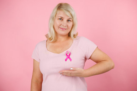 Closeup of pink badge ribbon on woman chest to support breast cancer cause. Healthcare, medicine and breast cancer awareness concept.の写真素材