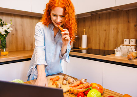 Portrait of smiling white Caucasian redhair woman with citrus lime lemon making juice standing in kitchen at home looking away, healthy lifestyle conceptの写真素材