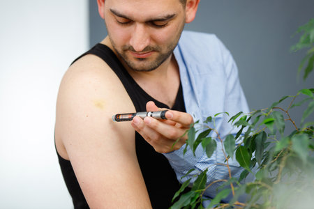 Man being at home with syringe making insulin injection to himself in body part shoulder and looking attentively.の写真素材