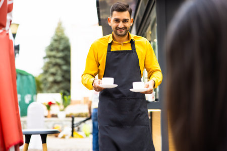 Coffee Business Concept - Beautiful Caucasian man smiling at camera offers disposable take away hot coffee at the modern coffee shopの写真素材