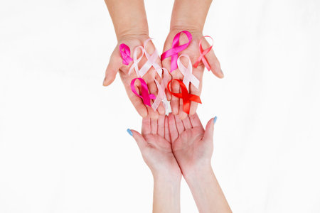 Hands holding pink ribbons on pink background, Breast cancer awareness and October Pink day, world cancer day, national cancer survivor dayの写真素材