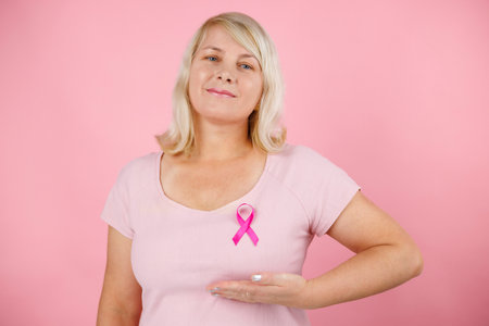 Mature woman with pink ribbon on color background. Breast cancer awareness concept.の写真素材