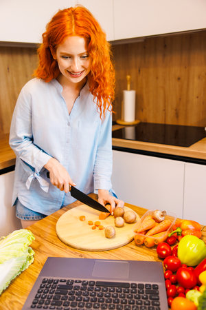 Beautiful young woman is preparing vegetable salad in the kitchen. Healthy Food. Vegan Salad. Diet. Dieting Concept. Healthy Lifestyle. Cooking At Home.の写真素材