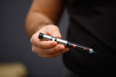 Male hand holding a syringe of insulin on blurry background for himself to make an injection, diabetes and life concept.の写真素材