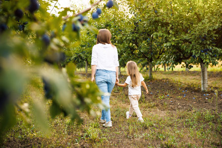 Happy mother and beautiful daughter with blonde hair walk in field of beautiful summer weather.の写真素材