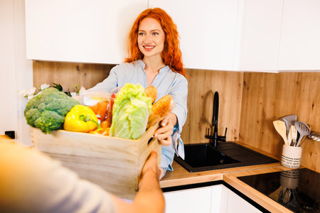 Woman attractive housewife in kitchen with grocery shopping bag, many fruits on counter. Healthy eating, cooking, vegetarian food, dieting and people concept.の写真素材