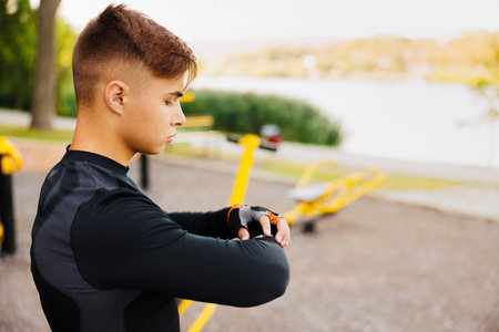 Sport Caucasian man looking smart watch at modern track runner using use smartwatch fitness bracelet Portrait fit male athlete checking result jogging in sportswear in street urban city park outdoorの写真素材