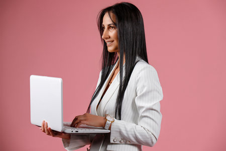 Business woman working online on a laptop - isolated over pink backgroundの写真素材