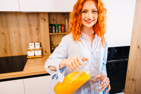 Beautiful woman making orange juice. Healthy eating lifestyle concept portrait of beautiful young woman preparing juice at home in kitchen.の写真素材