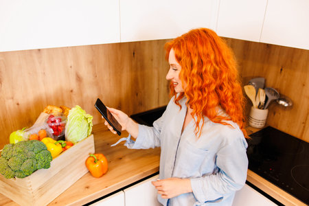 Beautiful young woman is preparing vegetable salad in the kitchen. Healthy Food. Vegan Salad. Diet. Dieting Concept. Healthy Lifestyle. Cooking At Home.の写真素材