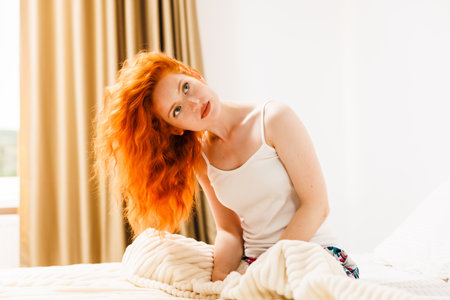 Portrait of a beautiful, attractive and sexy young woman, sensuality, looking to the side, with orange hair, in a luxury apartment.の写真素材
