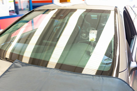 The windshield of the gray car reflected the lights from the car service, after it was repaired.の写真素材