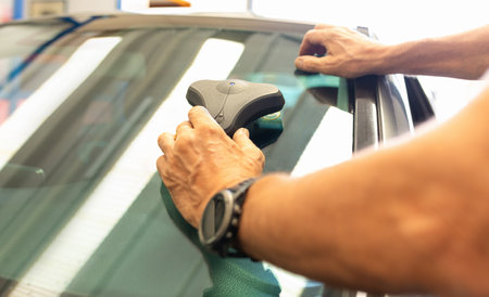 Mechanic car service changing windshield mirror by used technology replacing new windscreen or windshield of a car in auto service garage.の写真素材