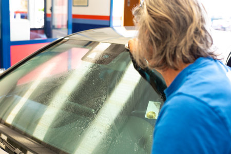 Auto service staff cleaning car rear windshield with microfiber cloth - car detailing and valeting conceptの写真素材