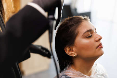 A woman with black hair getting her hair blown at a salon, happy and relaxedの写真素材