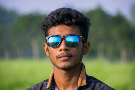 teenager boy portrait wearing coloring sunglasses in sunny daylight wearing full sleeve shirt in...