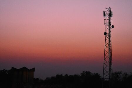 a mobile tower standing between the trees captured during sunsetの写真素材