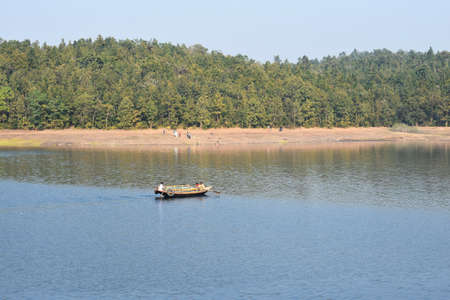 a boat floating in a blue lake just beside a islandの写真素材