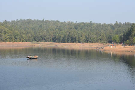 a boat floating over a blue lake with small wavesの写真素材