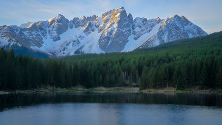 Image showing snow capped mountains overlooking a pine forest and calm lake. High resolution...