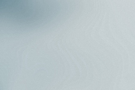 A faint blue and gray gradient with a fine grain texture offers a soft and diffused background.の写真素材