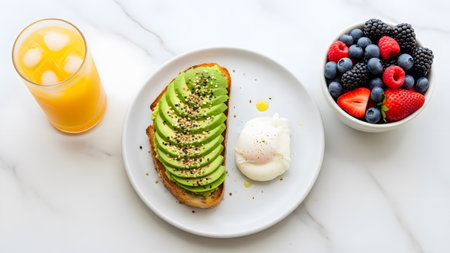 A vibrant and healthy breakfast featuring avocado toast, a poached egg, fresh berries, and orange...