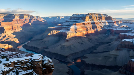 Grand canyon landscape with snow-dusted rock formations and winding river at sunriseの写真素材