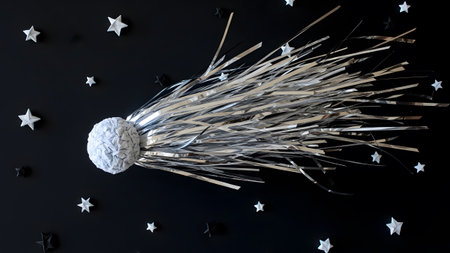 A silver comet with a textured sphere and streamers is set against a black background with...