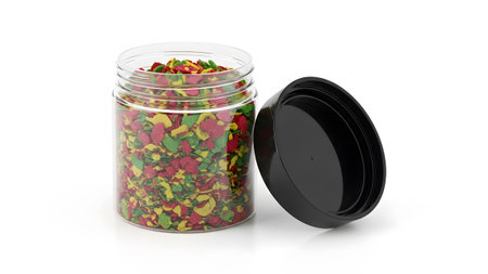 Fish showing clear plastic jar filled with colorful fish food flakes with black lid open white...