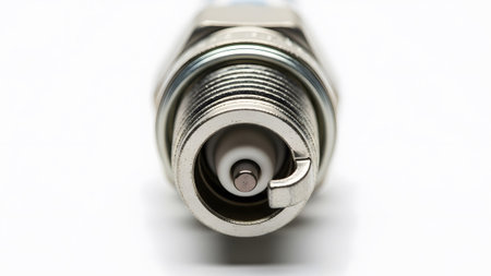 Close-up view of the threaded metal end and central electrode of a spark plug on a white background.