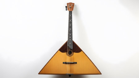 A traditional wooden balalaika with a dark wood accent on its triangular body rests against a...
